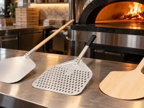 Palete pentru pizza din aluminiu și lemn lângă un cuptor profesional